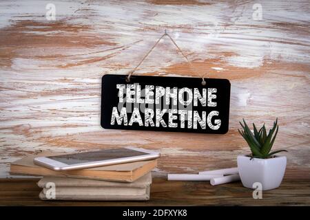 Marketing telefonico. Concetto aziendale. Telefono cellulare e libri su tavolo di legno Foto Stock