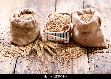 grani di grano in sacchi su tavola di legno Foto Stock