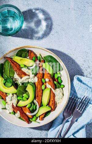 Concetto di cibo vegano. Insalata di patate dolci al forno con avocado ed edamame. Foto Stock