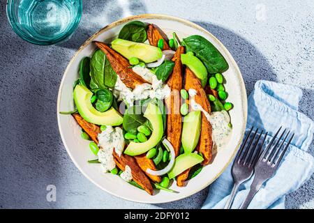 Concetto di cibo vegano. Insalata di patate dolci al forno con avocado ed edamame. Foto Stock