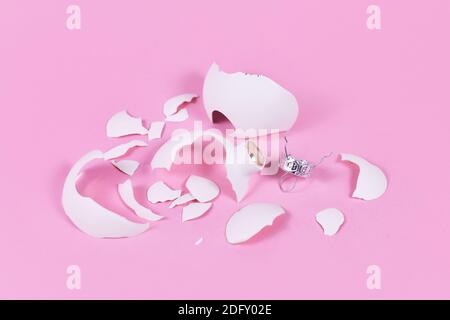 Rotto bianco albero di Natale vetro bauble frantumato in molti pezzi su sfondo rosa Foto Stock