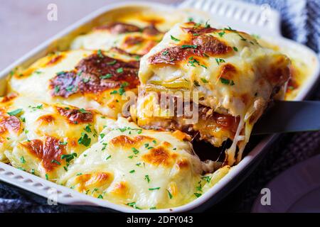 Tradizionale casseruola greca di patate e carne con formaggio - moussaka, fondo scuro. Cucina greca. Foto Stock