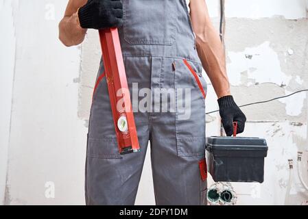 Uomo costruttore in uniforme con utensili da costruzione. Concetto di riparazione Foto Stock