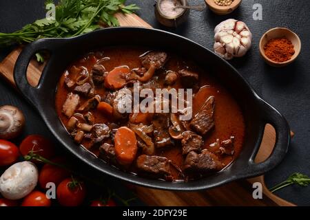 Manzo Bourguignon in una padella. Stufato con vino rosso, carote, cipolle, aglio, un bouquet garni, e guarnito con cipolle di perle, funghi e pancetta. Francese Foto Stock