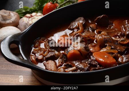 Manzo Bourguignon in una padella. Stufato con vino rosso, carote, cipolle, aglio, un bouquet garni, e guarnito con cipolle di perle, funghi e pancetta. Francese Foto Stock