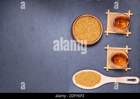 Tè di fenugreek, semi su una superficie di legno. Sollievo da anemia, perdita di gusto, febbre, medicina alternativa Foto Stock