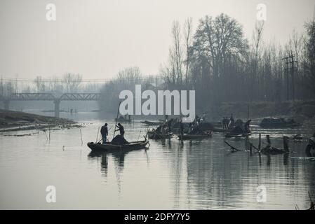 Ganderbal, India. 07 dicembre 2020. Gli uomini in barca estraggono la sabbia dal fiume sindh.A valle tra la Grande catena dell'Himalaya e la catena montuosa del PIR Panjal, il Kashmir è un luogo di bella semplicità e incontaminata bellezza naturale. Il Kashmir ha una varietà di terreni che vanno da laghi, montagne innevate, colline conifere baciate ai fiumi alimentati da ghiacciai. Credit: SOPA Images Limited/Alamy Live News Foto Stock