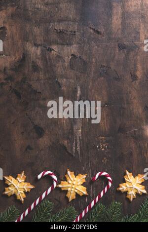 natale sfondo. composizione di natale con rami di abete, regali, dolci, biscotti, cannella su un fondo di legno scuro Foto Stock