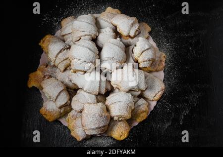 Biscotti fatti in casa sotto forma di bagel con marmellata di ripieno cosparso di zucchero in polvere su uno sfondo di legno. Messa a fuoco selettiva. Foto Stock