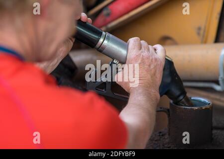 Uomo che rifornisce il trattore alla stazione di servizio. Pompaggio della benzina con pompa del carburante. Primo piano. Foto Stock