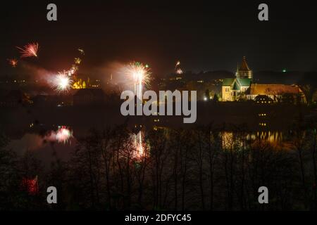 Fuochi d'artificio di Capodanno alla cattedrale di Ratzeburg con riflessi nel lago di notte, copia spazio nel cielo scuro Foto Stock
