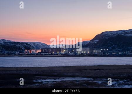 Inverno Teriberka. Paesaggio polare serale con il villaggio di Lodeynoye situato tra le colline polari. Foto Stock