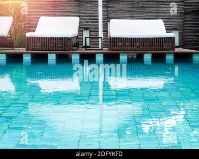 Lettini bianchi vuoti e puliti sulla terrazza in legno vicino alla piscina in estate. Foto Stock