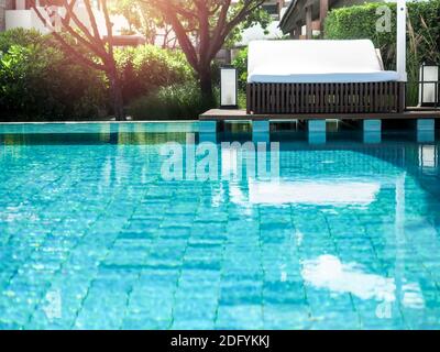 Lettini bianchi vuoti e puliti sulla terrazza in legno vicino alla piscina in estate. Foto Stock