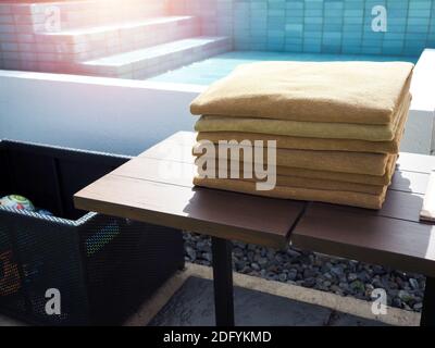 Pile di asciugamani puliti piegati è posto su un tavolo di legno accanto alla piscina. Foto Stock