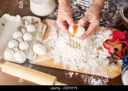 Cuoco esperto aggiungendo un uovo ad un mucchio di farina Foto Stock