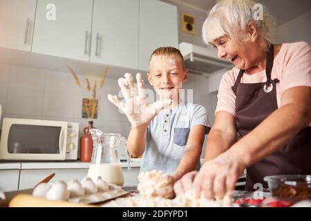 Gioiosa donna anziana e suo nipote che preparano l'impasto Foto Stock