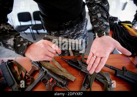 Bucarest, Romania - 22 marzo 2014: Dettagli con le mani di un ufficiale di polizia che mostra come funziona la vista laser di una pistola da 9mm. Foto Stock