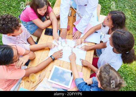 Gruppo di bambini impara ad un corso estivo per chimica nel campo delle lezioni durante le vacanze estive Foto Stock