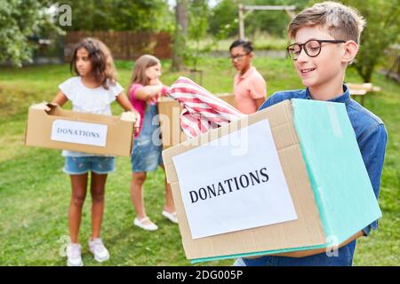 Gruppo di bambini come volontari che raccolgono donazioni per la raccolta di indumenti Foto Stock