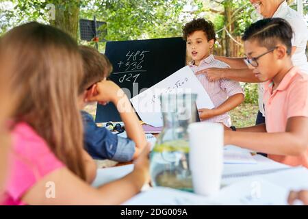 Gruppo di bambini impara la matematica in lezioni di insegnamento in estate corso di vacanza scolastica Foto Stock