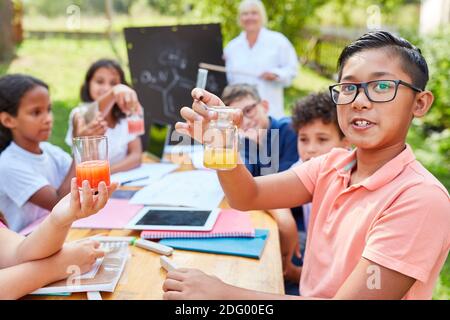 I bambini si divertono a fare esperimenti di chimica nelle lezioni di tutoring della scuola estiva Foto Stock