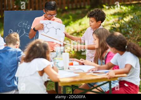 I bambini imparano insieme nella scuola estiva per la chimica nel campo di tutoraggio Foto Stock