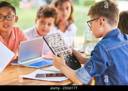 I bambini con calcolatrici imparano la matematica in estate corso di tutoring Foto Stock