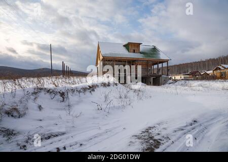 Un dacha in costruzione si trova su un poggio alla periferia del villaggio in inverno. Foto Stock