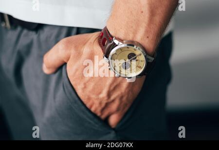 mano maschile con un orologio in una tasca di pantaloni Foto Stock