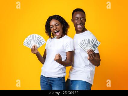 Coppia nera impressionabile che tiene mazzo di soldi Foto Stock