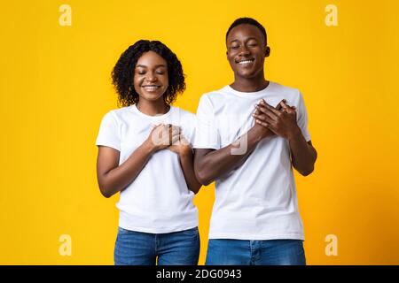 Donna e uomo pacifici che tengono entrambi i palmi sul petto Foto Stock