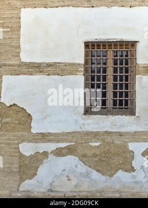 Finestra con una vecchia griglia di ferro su una parete Foto Stock