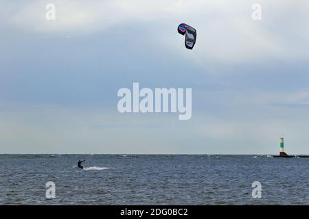 Un kite-boarder windsurf in una giornata con un faro sullo sfondo Foto Stock