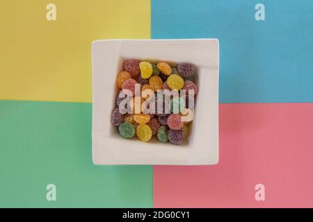 Rowntrees Jelly Tots dolci in ciotola su sfondo giallo pastello, blu rosa e verde - top down Foto Stock