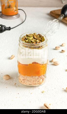 Parfait di zucca con briciole di Pistacchio in tazze di vetro vasetto Mason Foto Stock