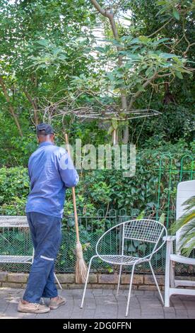 Alberton, Sudafrica - un lavoratore migrante nero fa il lavoro manuale di giardinaggio in un giardino residenziale Foto Stock