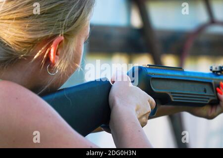 La ragazza tiene un fucile e prende mira. Messa a fuoco selettiva Foto Stock