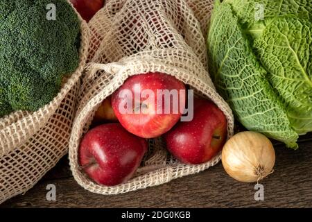 Mele e verdure in sacchetti ecologici riutilizzabili in rete di cotone biologico - concetto zero-waste Foto Stock