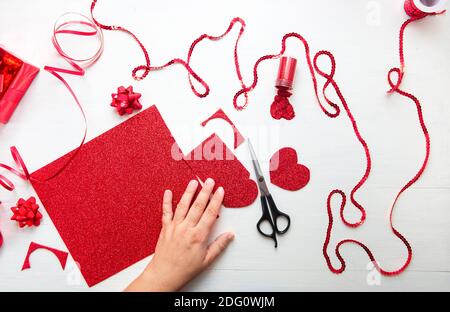 Mani donne che tengono un cuore valentino fatto a mano. Biglietto d'auguri regalo fatto a mano creazione, taglio. Vista dall'alto, disposizione piatta. San Valentino Foto Stock