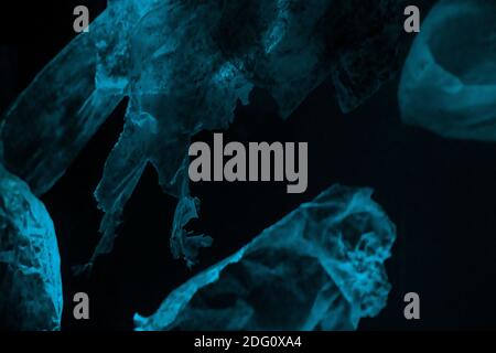 Vecchi pezzi di plastica galleggianti in profondità nell'oceano, in acqua isolata su nero. . Foto di alta qualità Foto Stock