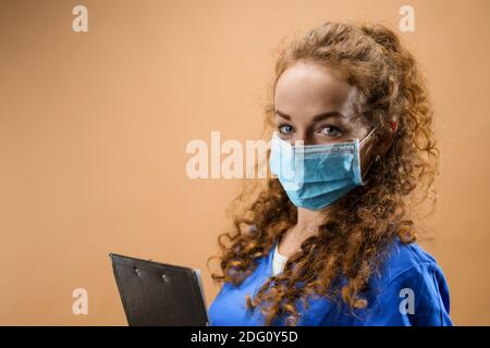 Giovane donna dottore in uno studio che tiene appunti, concetto di coronavirus. Foto Stock