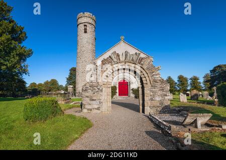 Repubblica d'Irlanda, Contea di Kildare, Castledermot, porta romanica di fronte alla Chiesa di San Giacomo che è la Chiesa d'Irlanda e una Torre rotonda del 10 ° secolo sullo sfondo. Foto Stock
