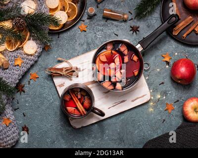 Composizione natalizia invernale con VIN brulé in tazza di ceramica marrone. Spazio di lavoro con busta marrone artigianale e ingredienti per il VIN brulé. Mano femmina Foto Stock