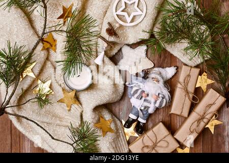 Accogliente composizione invernale. Stile Higge. Regali di Natale, decorazioni rustiche, Tinsel delle stelle d'oro e pullover a maglia calda su sfondo di legno. Disposizione piatta, da a. Foto Stock
