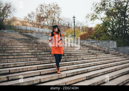 Attraente giovane donna in cappotto e cappello usa il telefono cellulare in città in autunno Foto Stock