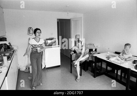 Vita moderna 1970s vita familiare classe operaia, madre, padre e bambino che è seduto sul tavolo da cucina nella cucina della loro casa a tre camere da letto su un nuovo moderno sviluppo edilizia nuova città Inghilterra 1977 notare il ferro sulla parete fuori del modo dietro la testa della donna. Milton Keynes, Buckinghamshire HOMER SYKES. Foto Stock