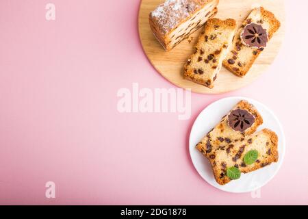 Torta fatta in casa con uvetta e persimmon secco su sfondo rosa pastello. Vista dall'alto, disposizione piatta, spazio per la copia. Foto Stock