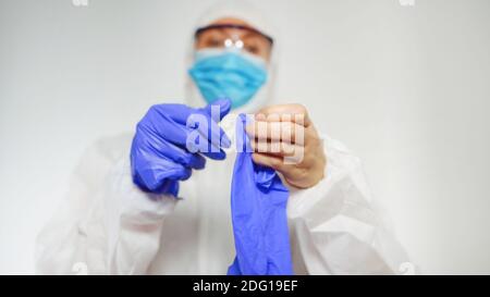 Il lavoratore medico in tuta protettiva indossa i guanti. Foto Stock