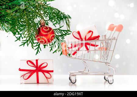 Shopping di Capodanno. Mini cart con scatole regalo su sfondo bianco. Foto Stock